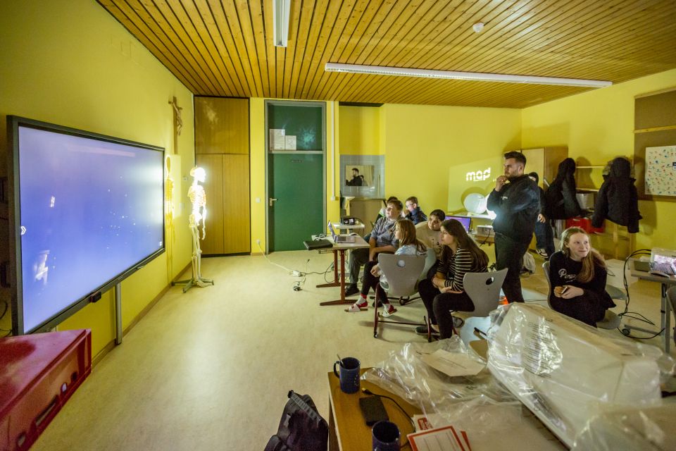 Bild der KUK-up Veranstaltung - Schüler starren gebannt auf einen großen Bildschirm in einem abgedunkelten Raum