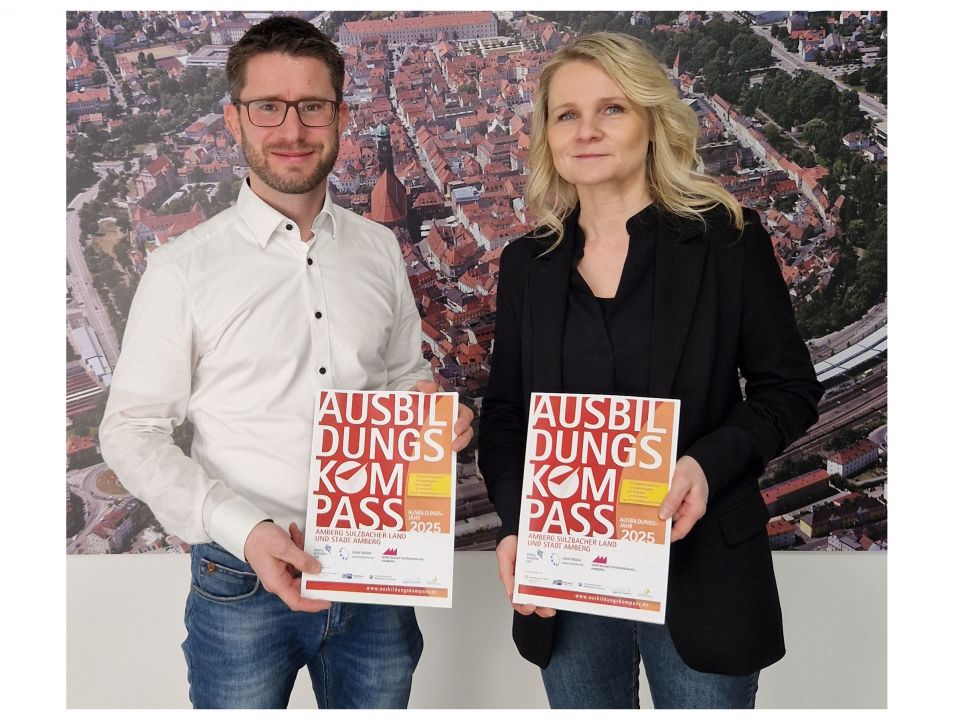 Ausbildungskompass 2024 für das Jahr 2025 - 2 Personen der Wirtschaftsförderung halten jeweils ein Cover des Ausbildungskompasses in den Händen.